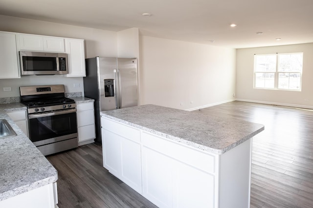 kitchen featuring light countertops, a center island, stainless steel appliances, white cabinets, and dark wood-style flooring