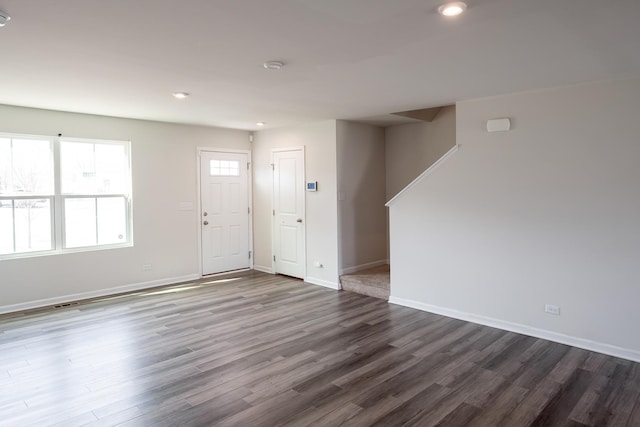 empty room with dark wood-type flooring, baseboards, and recessed lighting