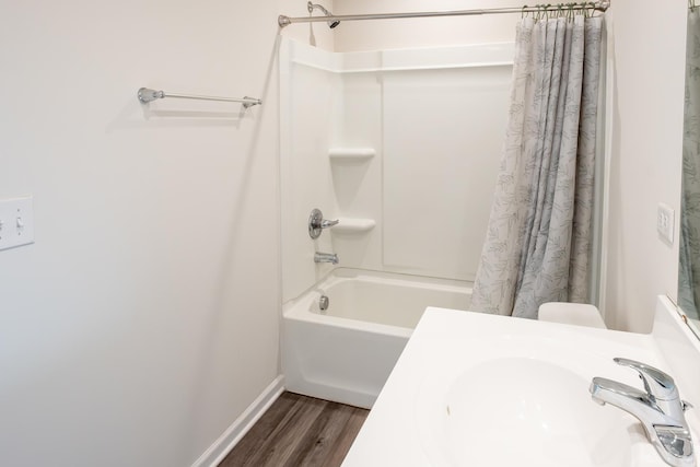 bathroom with baseboards, a sink, shower / bath combination with curtain, and wood finished floors