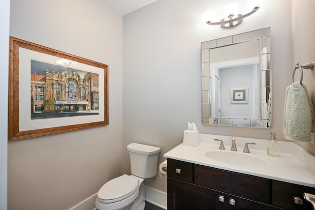 half bathroom featuring vanity, baseboards, and toilet