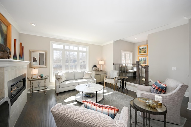 living area featuring baseboards, ornamental molding, recessed lighting, a tiled fireplace, and wood finished floors