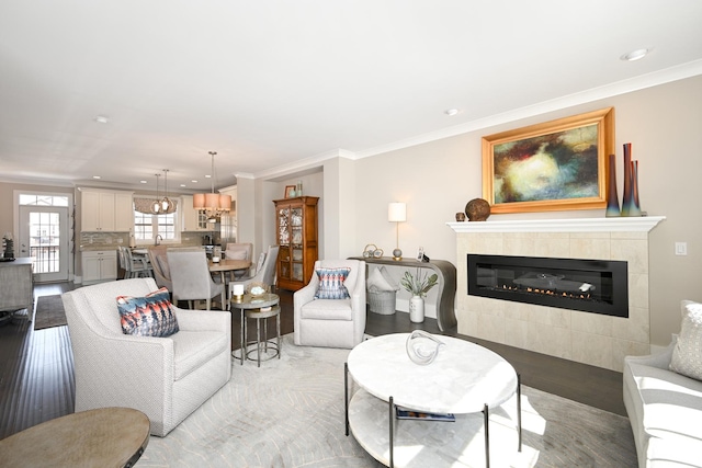 living room featuring recessed lighting, a fireplace, light wood finished floors, and crown molding