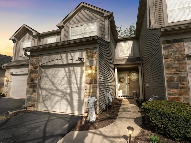 view of front of house featuring driveway, stone siding, and a garage