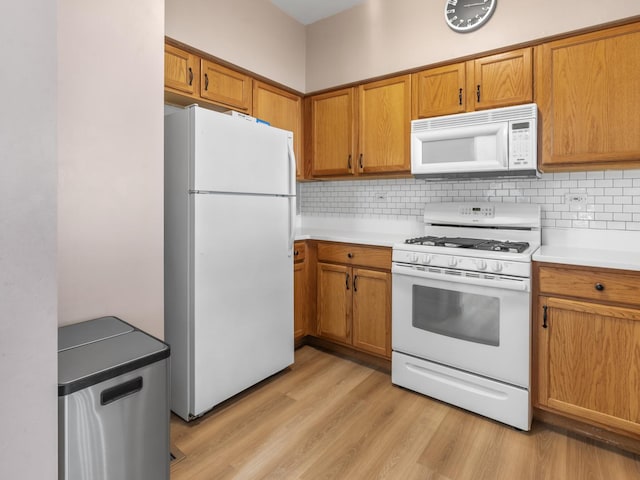 kitchen with tasteful backsplash, light wood-style flooring, brown cabinetry, and white appliances
