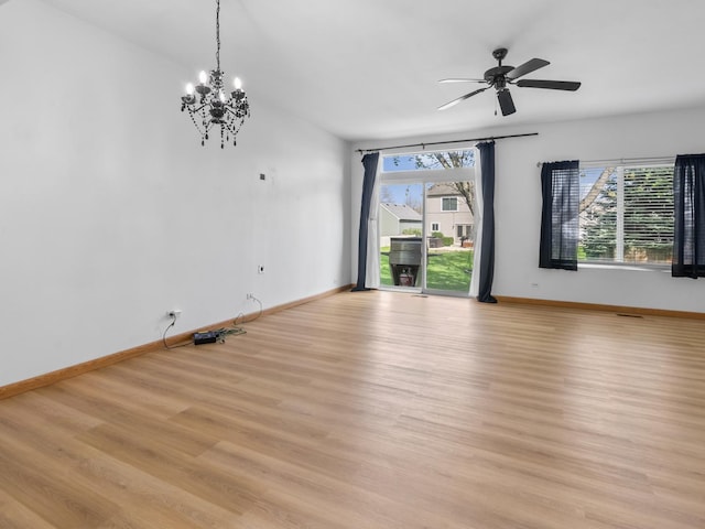 unfurnished room featuring light wood-type flooring, ceiling fan with notable chandelier, and baseboards