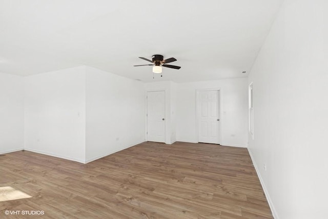 unfurnished room with a ceiling fan, light wood-style floors, and baseboards