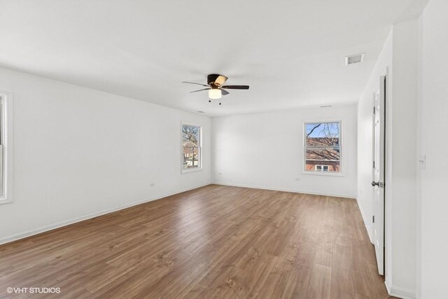 unfurnished room with baseboards, wood finished floors, visible vents, and ceiling fan