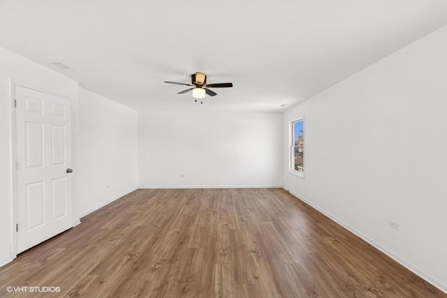 spare room featuring baseboards, ceiling fan, and wood finished floors