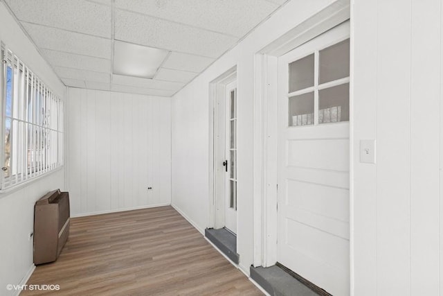 empty room featuring a drop ceiling, baseboards, and wood finished floors