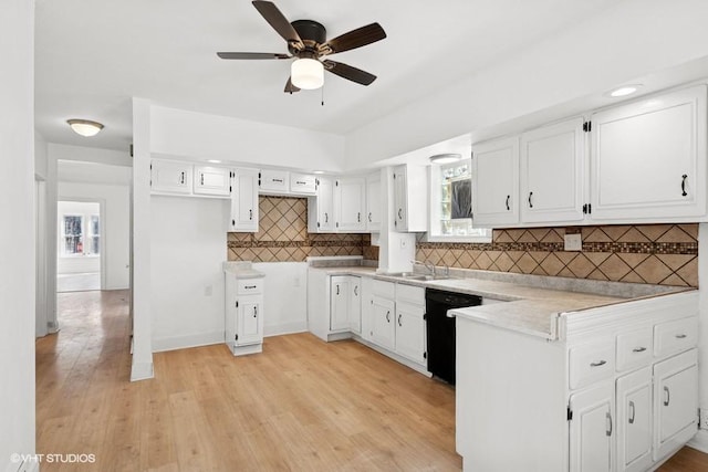 kitchen with light wood-type flooring, a ceiling fan, a sink, black dishwasher, and light countertops