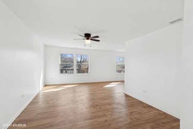 unfurnished room featuring wood finished floors, a ceiling fan, visible vents, and baseboards