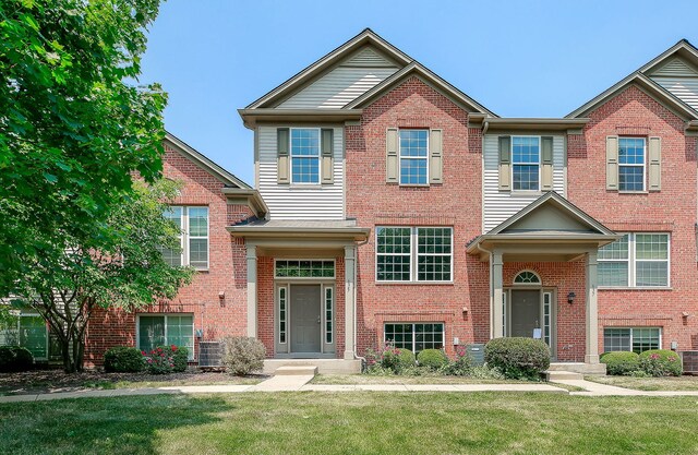 view of property with brick siding and a front lawn