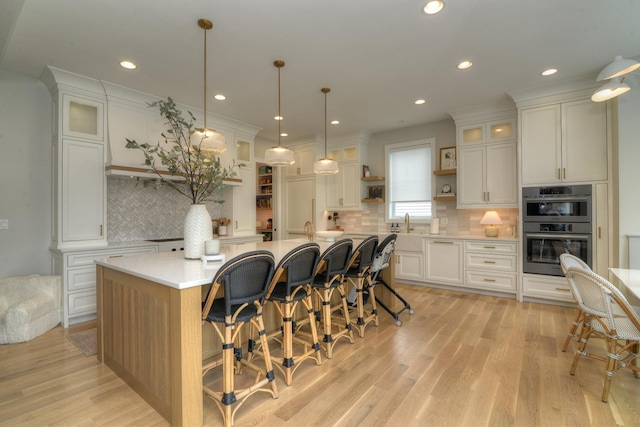 kitchen with double oven, open shelves, white cabinets, and light countertops