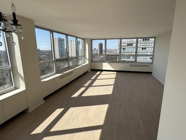 unfurnished sunroom featuring a city view, radiator heating unit, and a chandelier