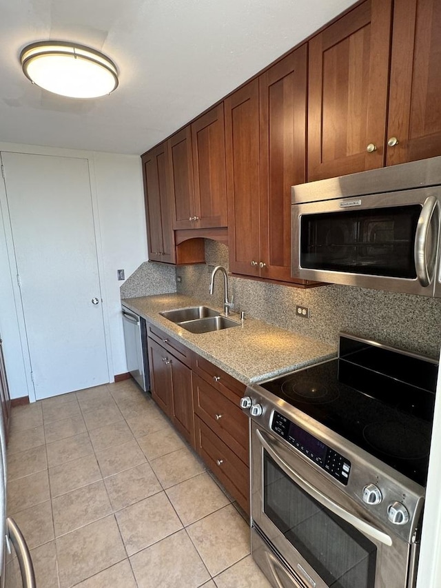 kitchen with a sink, stainless steel appliances, light tile patterned flooring, and decorative backsplash