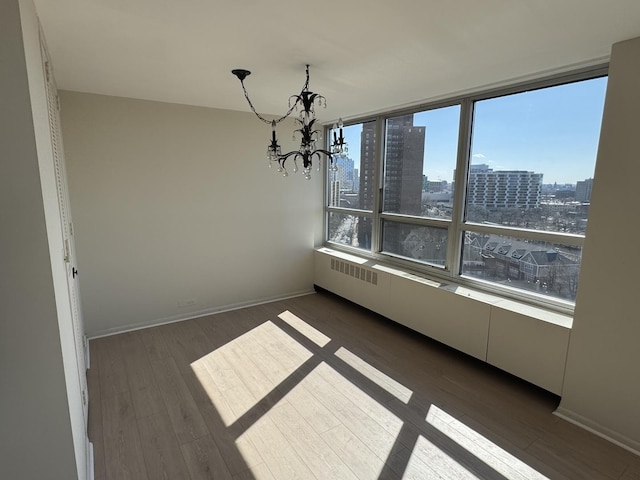 unfurnished dining area with dark wood-style floors, a city view, baseboards, and an inviting chandelier