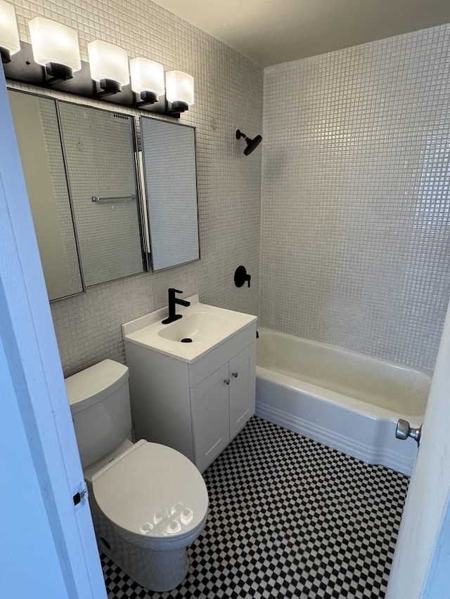 bathroom with shower / bath combination, toilet, tile walls, and vanity