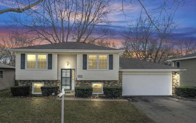 split foyer home with aphalt driveway, a garage, a front yard, and a shingled roof