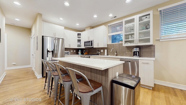 kitchen with visible vents, baseboards, a breakfast bar area, appliances with stainless steel finishes, and backsplash