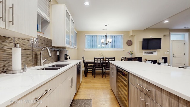 kitchen with wine cooler, light wood-style floors, a sink, backsplash, and dishwasher