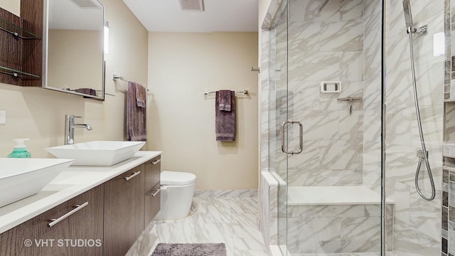 bathroom featuring double vanity, visible vents, a stall shower, a sink, and toilet
