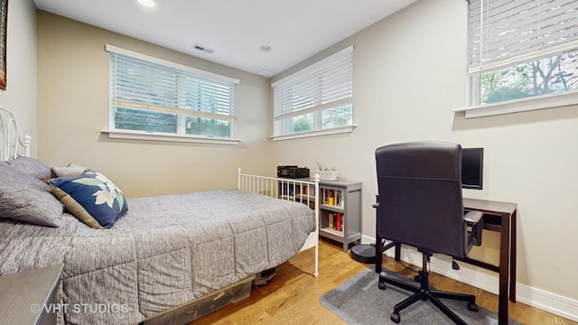 bedroom with visible vents, multiple windows, and wood finished floors