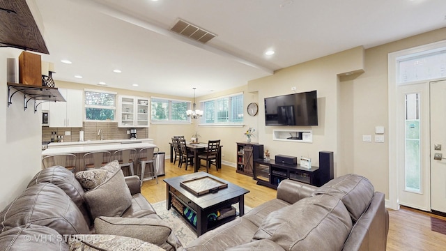 living area with visible vents, recessed lighting, light wood-style flooring, and an inviting chandelier
