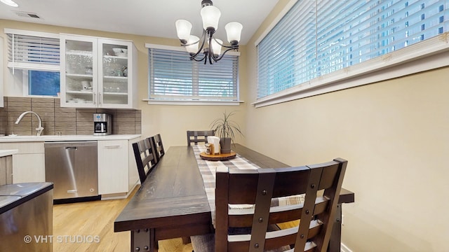 dining space with a notable chandelier, light wood-type flooring, and visible vents