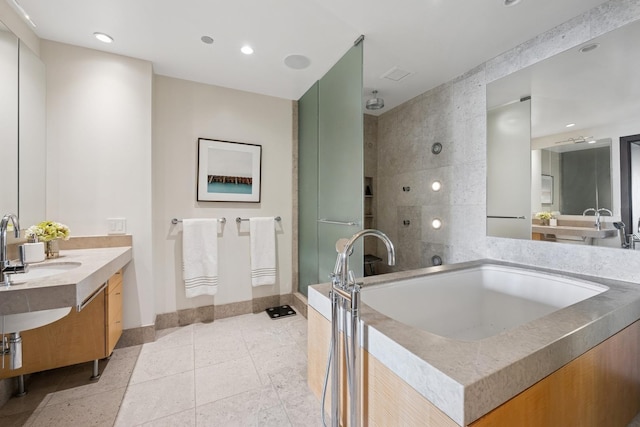 bathroom with a tile shower, vanity, recessed lighting, tile patterned floors, and baseboards