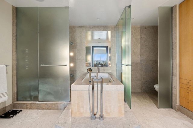 full bath with a bath, toilet, a sink, tile walls, and a stall shower