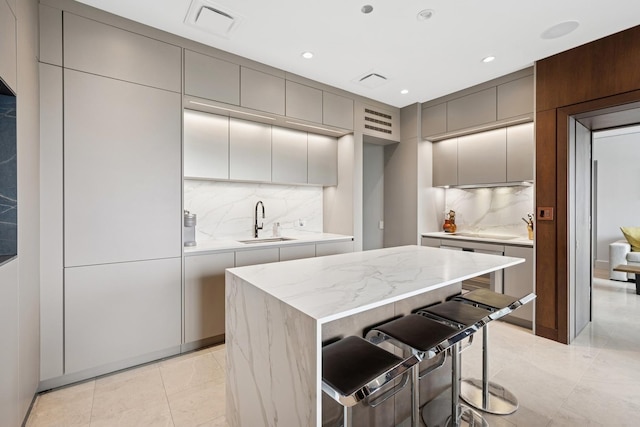 kitchen with a kitchen breakfast bar, gray cabinetry, visible vents, modern cabinets, and a sink