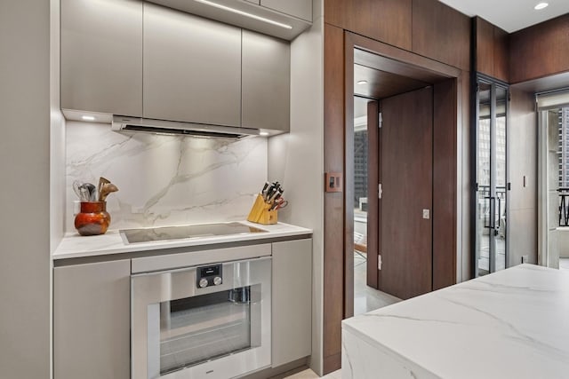 bar with decorative backsplash, extractor fan, oven, and black electric cooktop