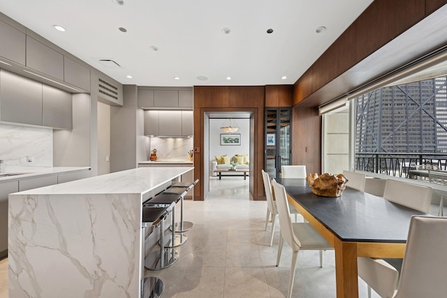 kitchen with modern cabinets, a kitchen island, gray cabinets, decorative backsplash, and a breakfast bar area