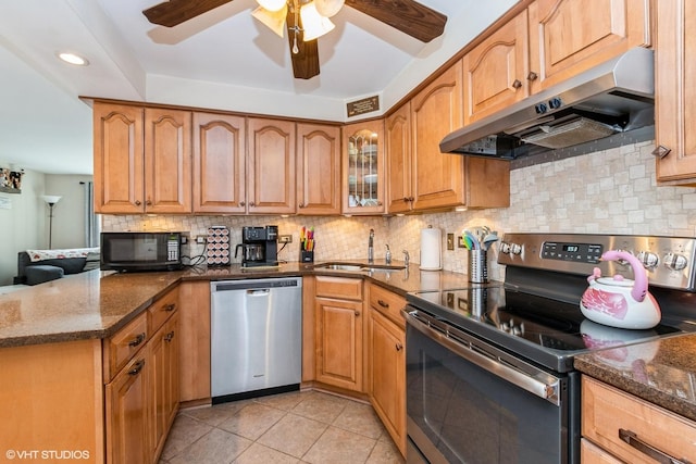 kitchen with dark stone countertops, a sink, stainless steel appliances, and under cabinet range hood