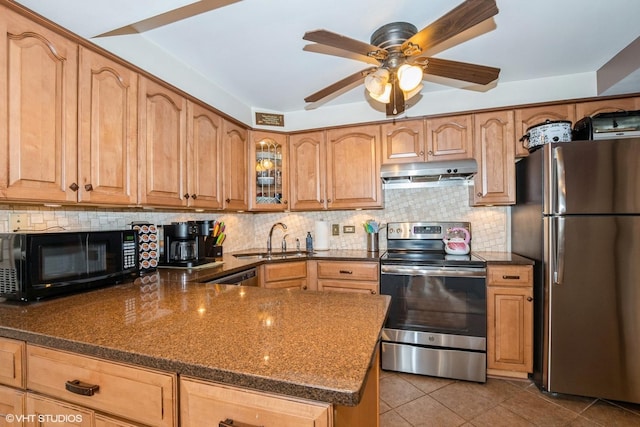 kitchen featuring dark stone counters, tile patterned floors, under cabinet range hood, appliances with stainless steel finishes, and a sink