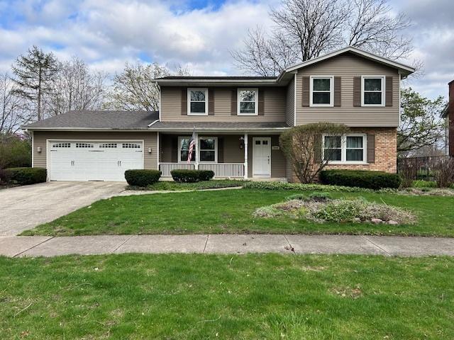 traditional-style home featuring a porch, concrete driveway, a front lawn, and a garage