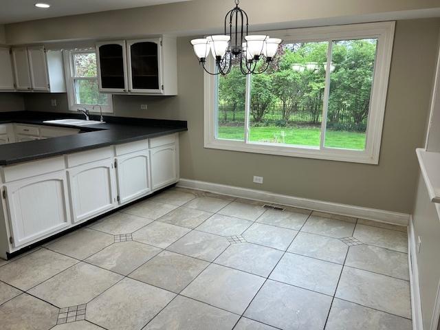 kitchen featuring a sink, dark countertops, light tile patterned floors, and a healthy amount of sunlight