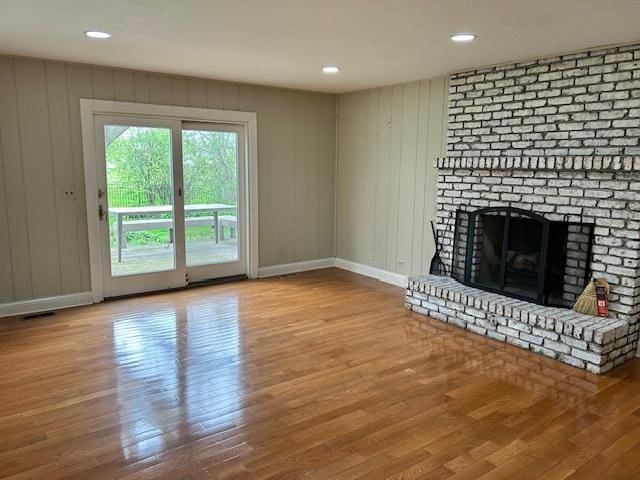 unfurnished living room with baseboards, a fireplace, recessed lighting, and wood finished floors