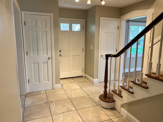 entryway featuring baseboards, stairs, light tile patterned floors, and a wealth of natural light