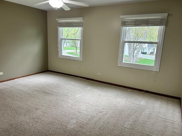 carpeted spare room featuring baseboards and ceiling fan