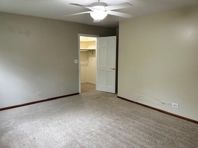 spare room featuring ceiling fan, light colored carpet, and baseboards