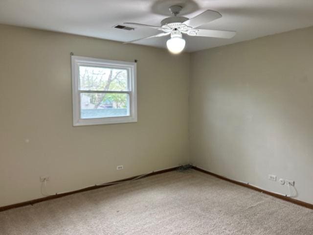 empty room with baseboards, light carpet, a ceiling fan, and visible vents