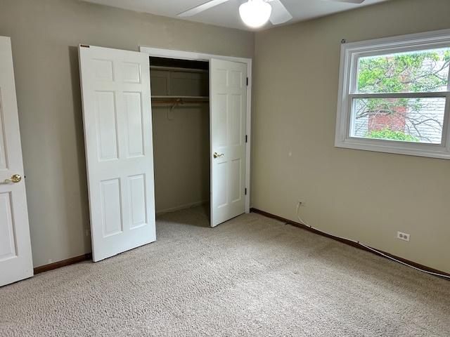 unfurnished bedroom featuring baseboards, ceiling fan, light carpet, and a closet