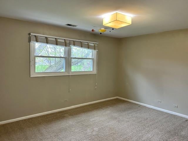empty room featuring baseboards, carpet, and visible vents
