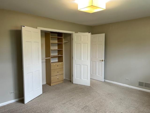 unfurnished bedroom with light colored carpet, baseboards, visible vents, and a closet