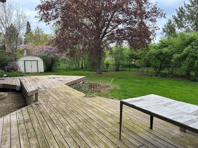 deck featuring a storage shed, a yard, an outbuilding, and a fenced backyard