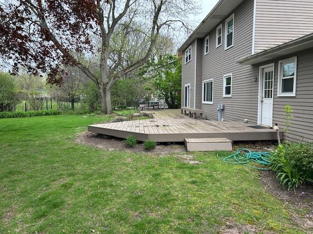 wooden terrace featuring a lawn and fence