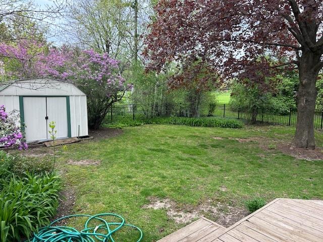 view of yard with a fenced backyard, a storage unit, an outdoor structure, and a wooden deck