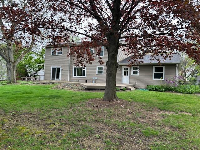back of property featuring a wooden deck, a yard, and fence