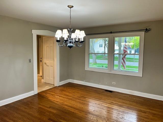unfurnished dining area featuring baseboards, wood finished floors, and a chandelier